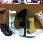 Several custom orthoses and shoes on a workbench